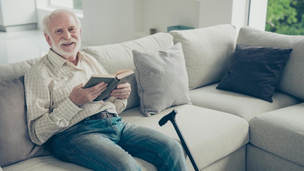elderly man reading on a sofa